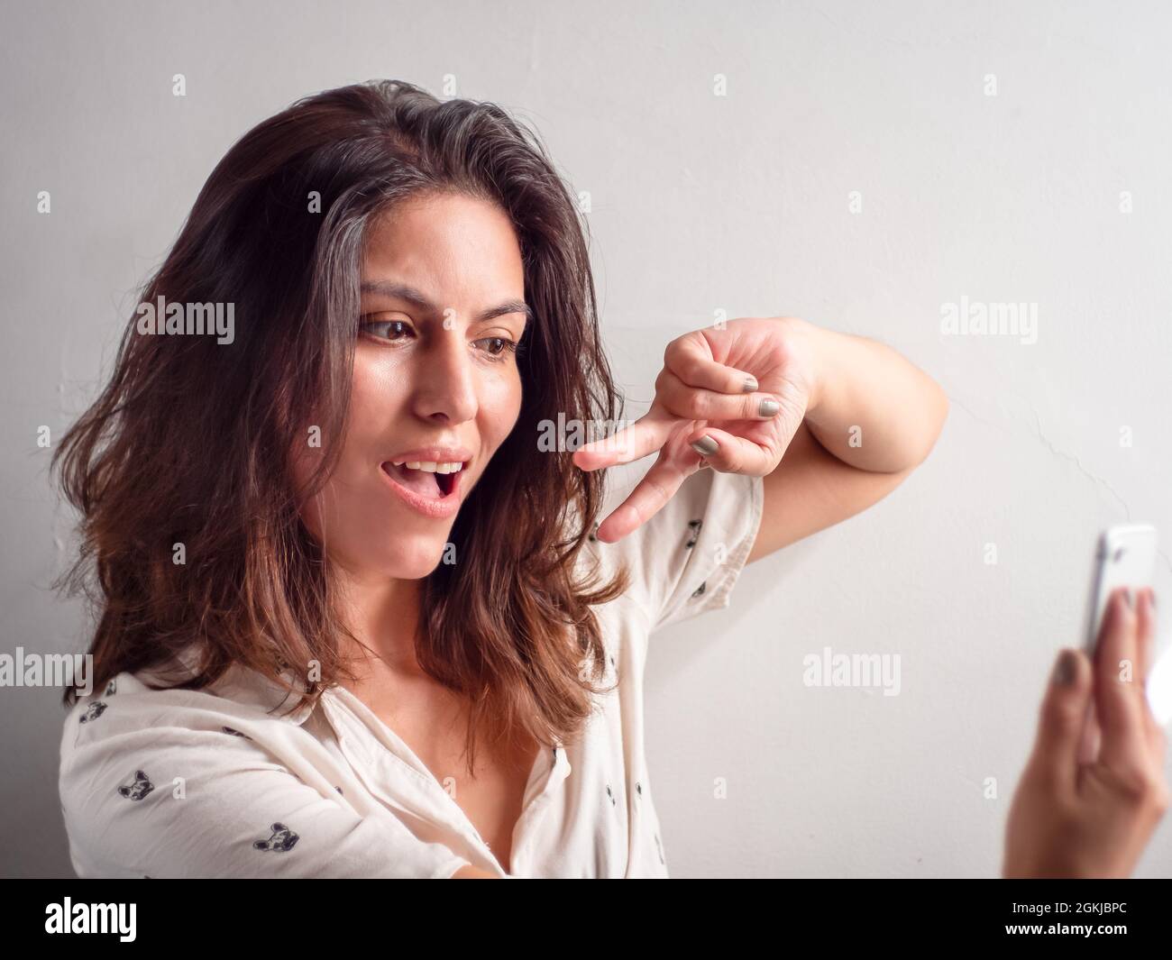 Jeune femme péruvienne à cheveux bruns pose pour un Selfie avec son smartphone Banque D'Images