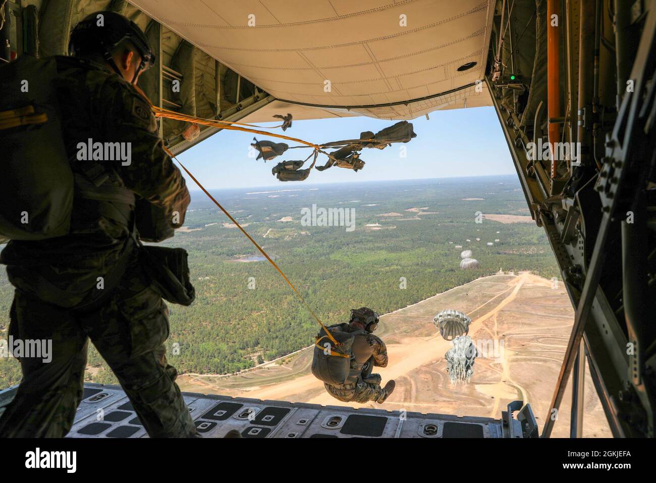 Un ciel bleu et une visibilité claire pendant que les soldats du quartier général et de la compagnie de quartier général, du Commandement des affaires civiles et des opérations psychologiques de l'armée américaine (aéroporté) sortent d'un avion KC-130 de la marine américaine pendant un saut de ligne statique au-dessus de la zone de dépôt de Sicile, ft. Bragg, N.C., 1er mai 2021. Le saut en queue a permis aux soldats de rafraîchir leurs compétences et de mettre à jour leurs qualifications de saut. Banque D'Images