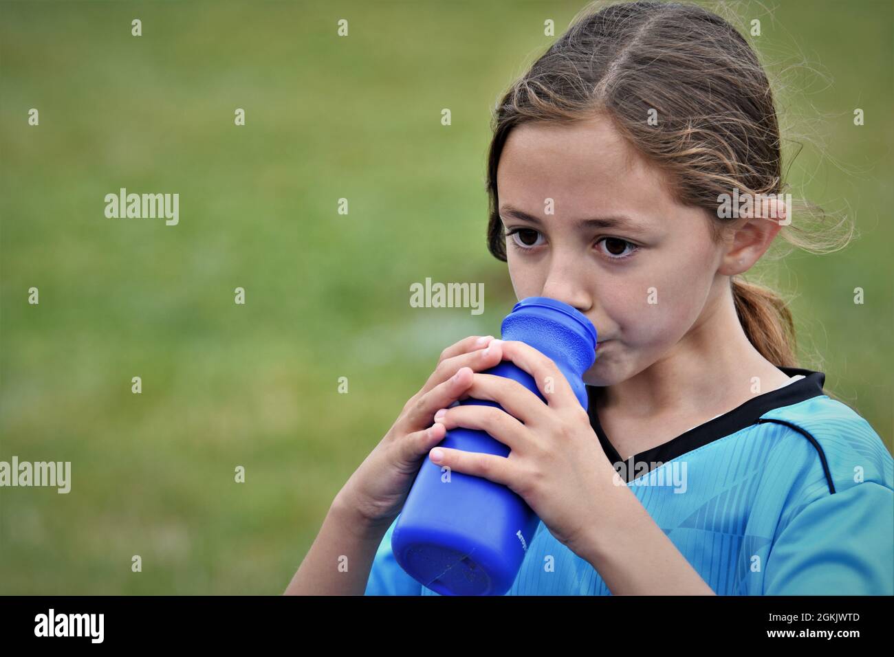 fille de 9 ans à la moitié de son premier match de football boire liquide et pointant vers l'équipe adverse qu'ils ont perdu à copier l'espace texte Banque D'Images