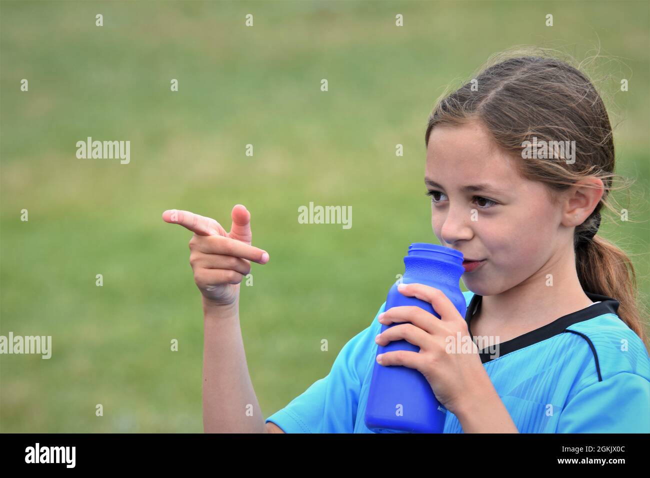 fille de 9 ans à la moitié de son premier match de football boire liquide et pointant vers l'équipe adverse qu'ils ont perdu à copier l'espace texte Banque D'Images