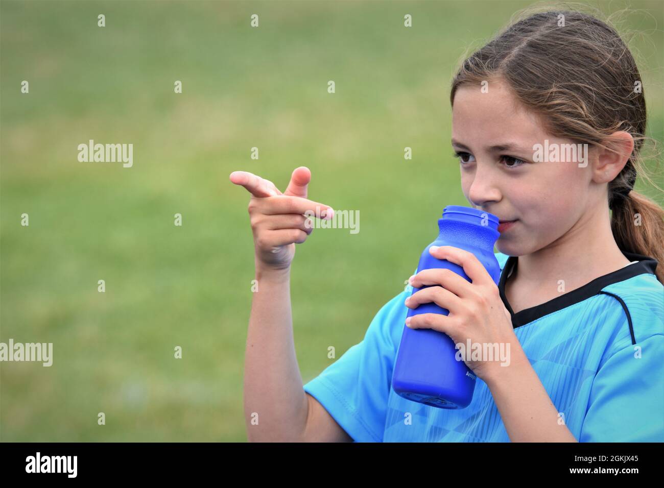 fille de 9 ans à la moitié de son premier match de football boire liquide et pointant vers l'équipe adverse qu'ils ont perdu à copier l'espace texte Banque D'Images