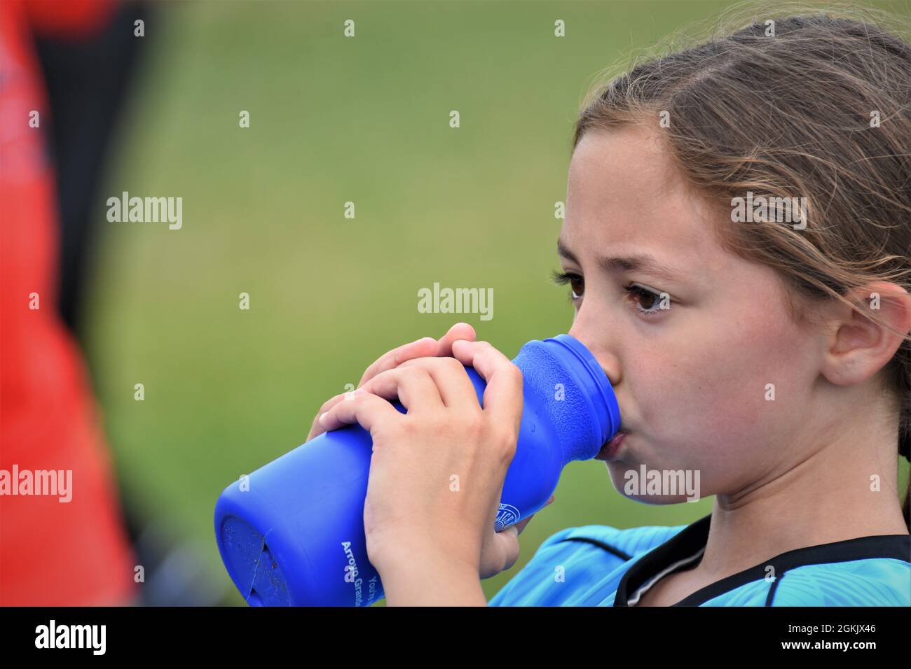 fille de 9 ans à la moitié de son premier match de football boire liquide et pointant vers l'équipe adverse qu'ils ont perdu à copier l'espace texte Banque D'Images
