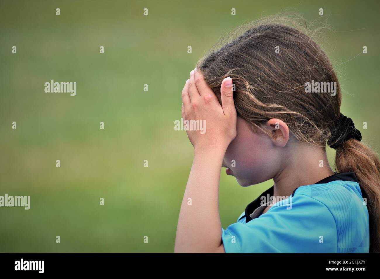 fille de 9 ans à la moitié de son premier match de football boire liquide et pointant vers l'équipe adverse qu'ils ont perdu à copier l'espace texte Banque D'Images