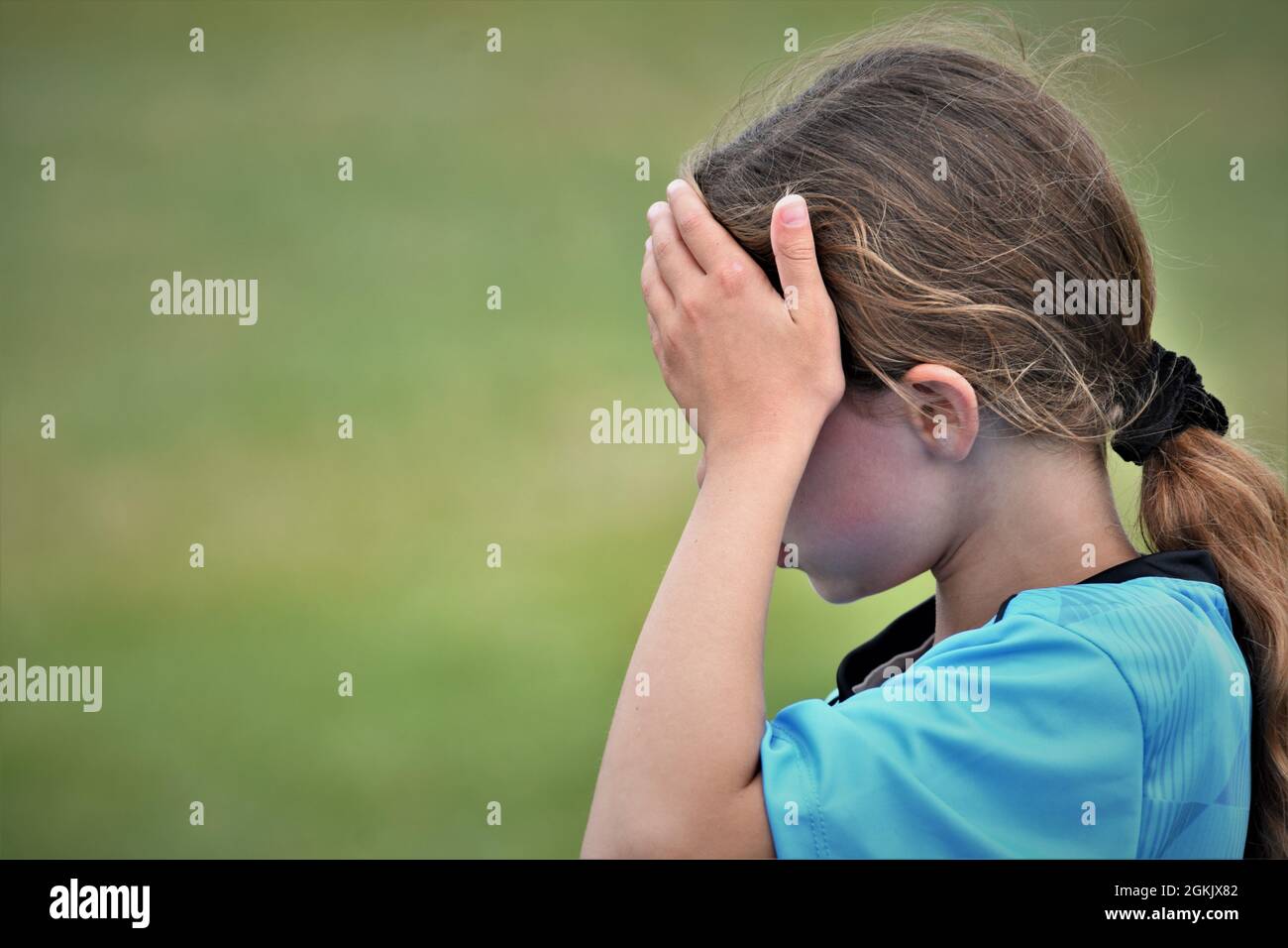 fille de 9 ans à la moitié de son premier match de football boire liquide et pointant vers l'équipe adverse qu'ils ont perdu à copier l'espace texte Banque D'Images