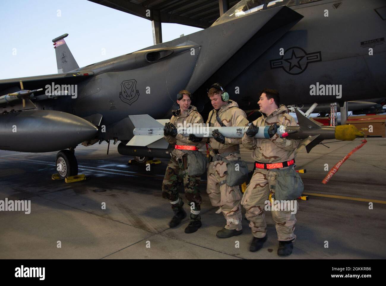 Trois aviateurs de chargement d'armes du 389e Escadron de combat transportent un missile Air Intercept à un F-15E Strike Eagle à la base aérienne de Mountain Home, Idaho, le 19 mai 2021. Les aviateurs s'entraînent tout en portant un équipement de protection personnelle orienté mission dans le cadre d'un exercice de phase II, qui prépare les aviateurs à travailler efficacement dans un environnement contesté. Banque D'Images