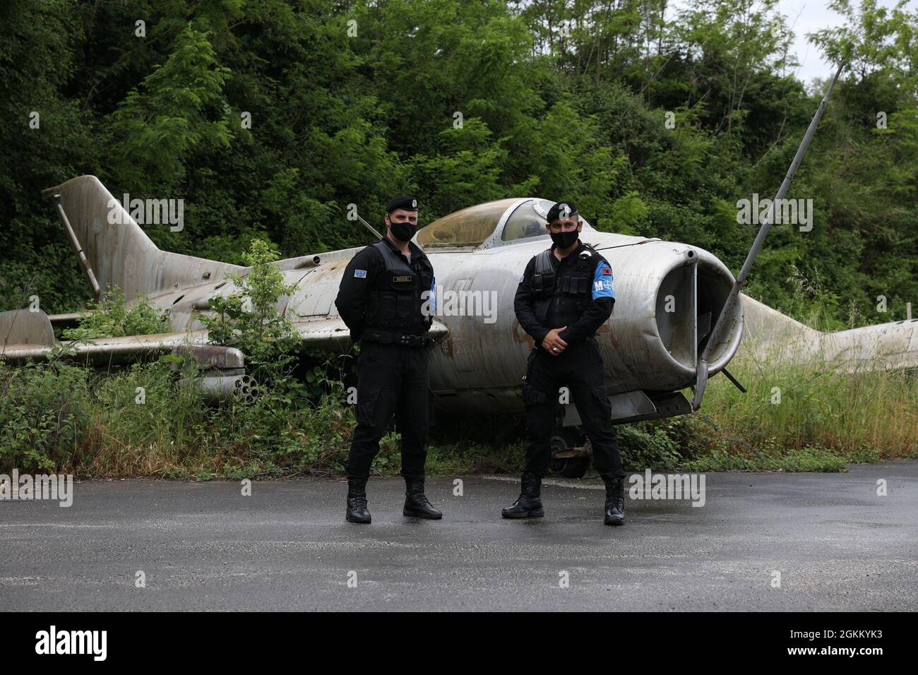 La police militaire albanaise se trouve à côté d'un avion désaffecté à  l'extérieur d'un ancien soute de stockage de munitions le 21 mai 2021, à un  tarmac sur la base aérienne de