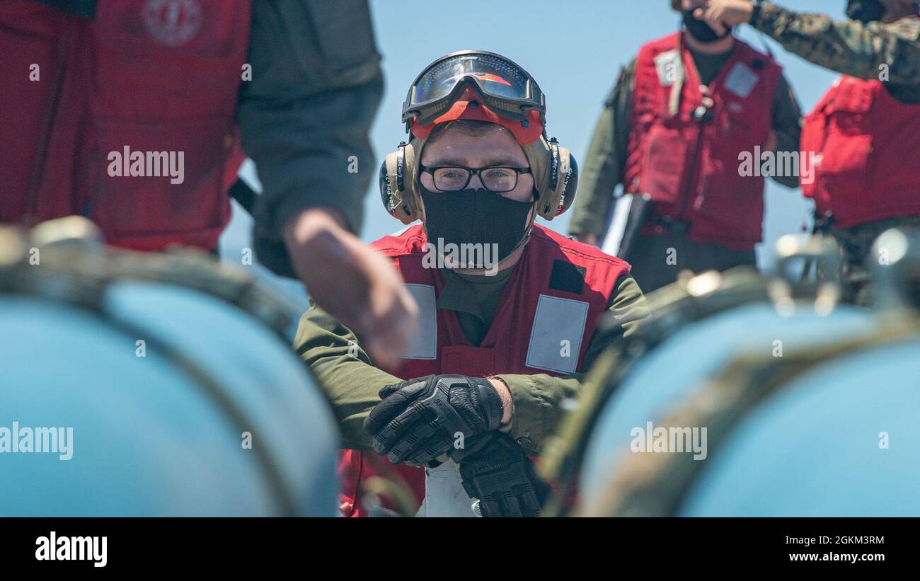 OCÉAN PACIFIQUE (21 mai 2021) Une marine américaine avec le Marine Attack Squadron (VMA) 214, 11e unité expéditionnaire maritime (MEU), observe Marines charger des munitions d'attaque directe à joint inerte sur des Harriers AV-8B à bord du navire d'assaut amphibie USS Essex (LHD 2), mai 21. Des Marines et des marins du 11e MEU et du groupe de prêt amphibie d'Essex (ARG) sont en cours de formation intégrée au large des côtes du sud de la Californie. Banque D'Images