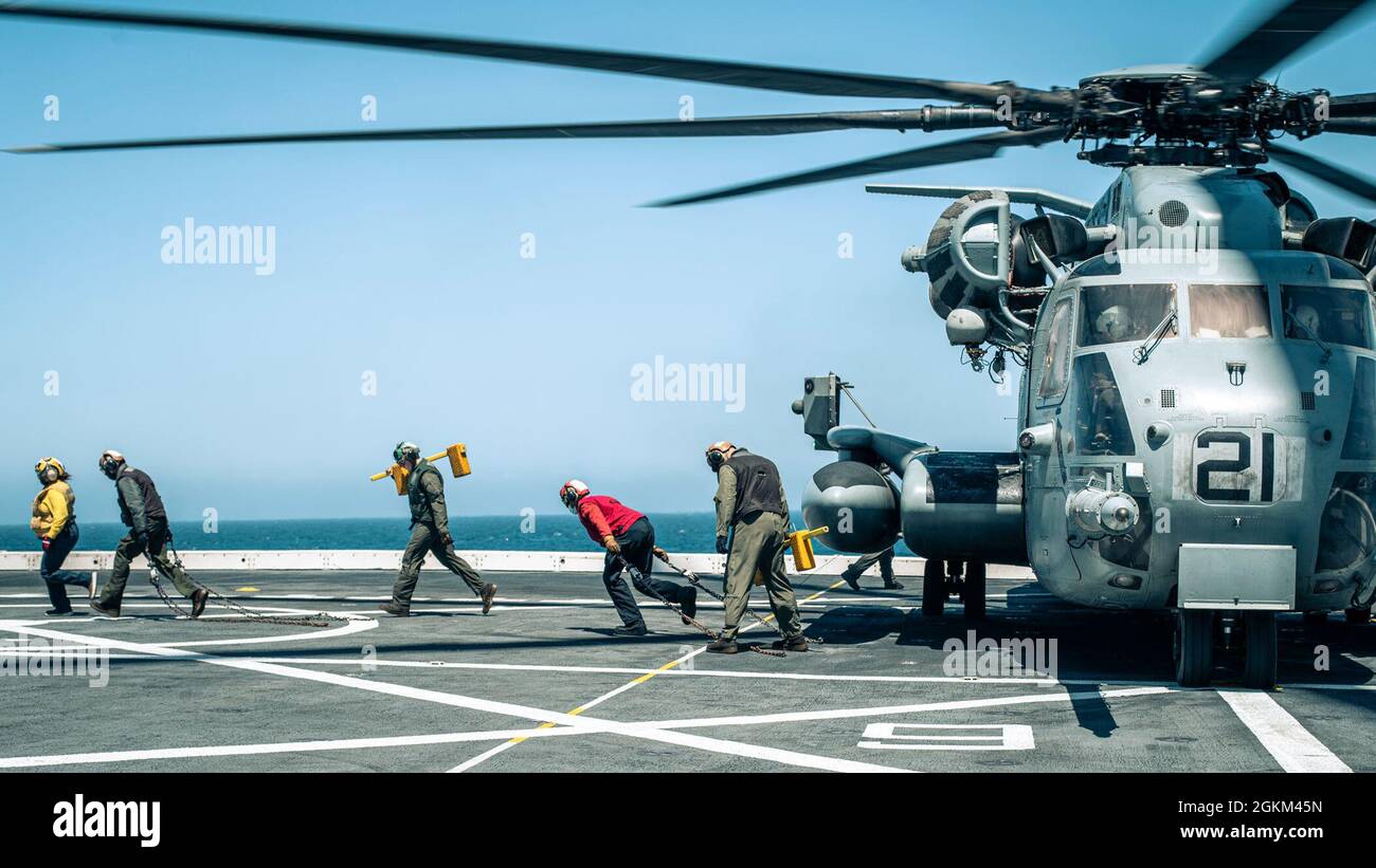 OCÉAN PACIFIQUE (21 mai 2021) les Marines des États-Unis avec le Marine Medium Tiltrotor Squadron (VMM) 165 (renforcé), la 11e Marine Expeditionary Unit (MEU), et les marins affectés au quai de transport amphibie USS Portland (LPD 27) retirent les chaînes et les cales de roue d'un CH-53E Super Stallion pendant les opérations de vol à bord de Portland, mai 21. Des Marines et des marins du 11ème MEU et du Essex Amphiobie Ready Group (ARG) sont en cours de formation intégrée au large des côtes du sud de la Californie. Banque D'Images