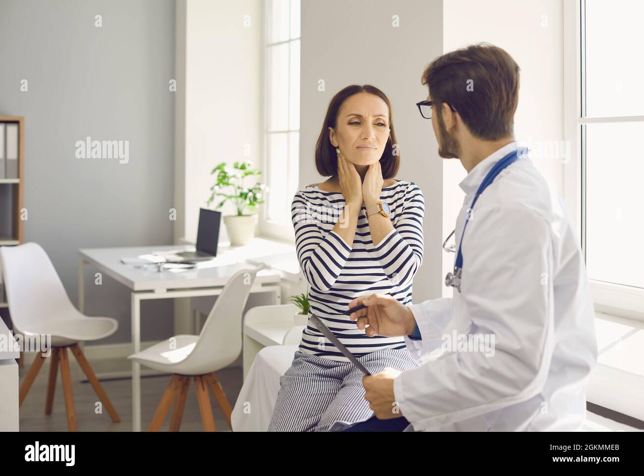 Femme souffrant de douleurs au cou et de glandes amygdales douloureuses qui voit son médecin à la clinique ou à l'hôpital Banque D'Images