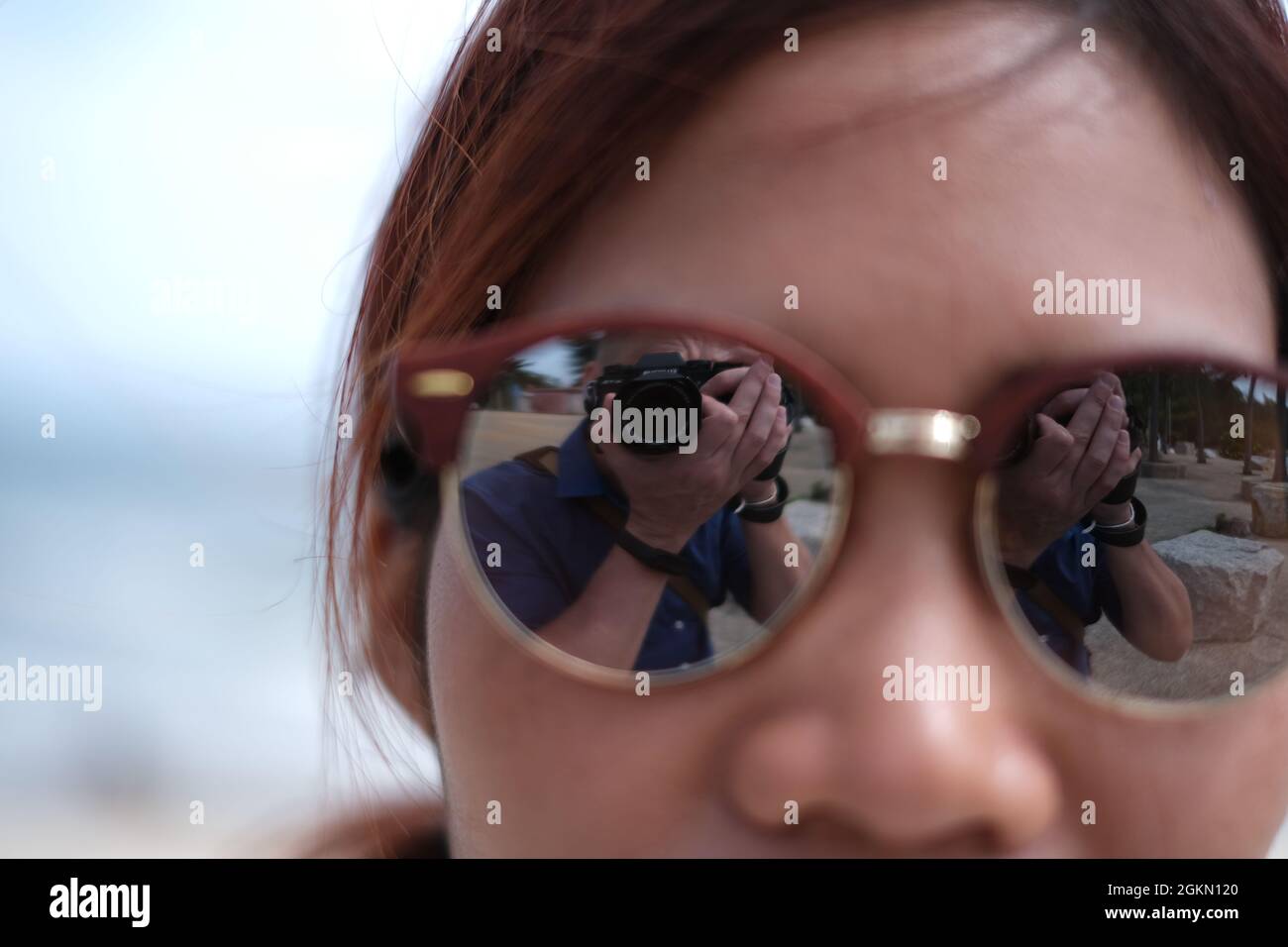 Le photographe lui-même réfléchit dans des lunettes de soleil de femme asiatique attrayante Banque D'Images