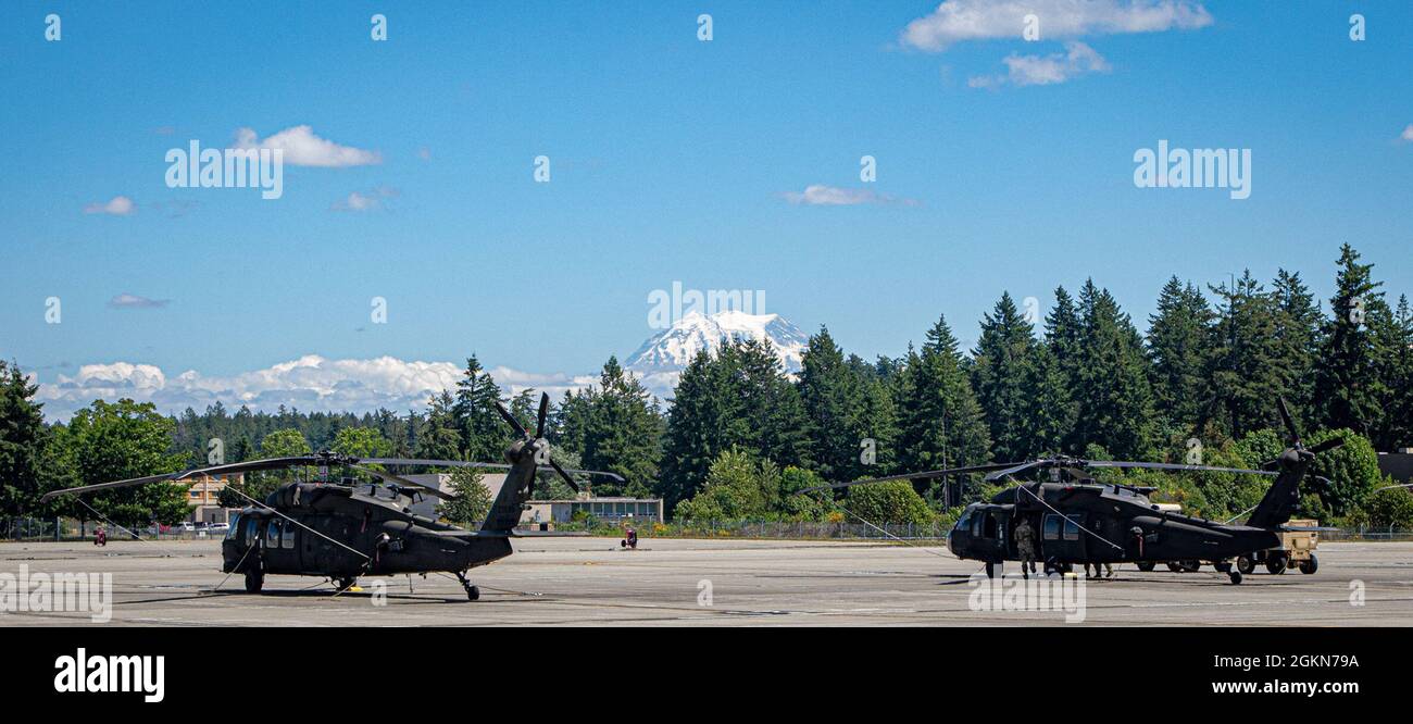 LES hélicoptères UH-60 Blackhawk affectés à la compagnie B, 2-158 Bataillon des hélicoptères d'assaut, 16e Brigade de l'aviation de combat, sont mis en scène pendant les opérations de routine à la base interarmées Lewis McChord, Washington, le 3 juin 2021. Le Mont Rainier est visible en arrière-plan, un volcan dormant et une partie de l'anneau de feu du Pacifique. Banque D'Images