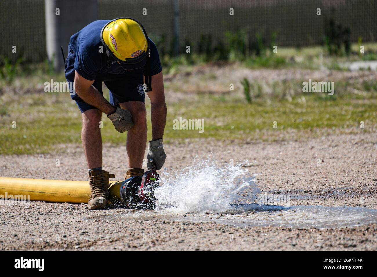 Une personne qui participe à la formation sur les incendies vivants libère de l'eau du tuyau d'incendie, le 5 juin 2021, sur F.E. Base aérienne de Warren, Wyoming. Cette formation a pour but d’évaluer les réponses et l’opportunité des aviateurs dans un scénario réel. Banque D'Images