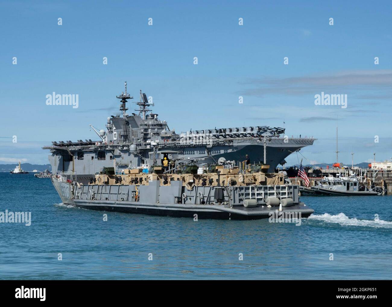 WHITE BEACH, Japon (juin 10, 2021) Un service d'embarcation quitte le petit bassin pour bateaux sur le commandant, activités de la flotte installation navale d'Okinawa White Beach, Okinawa (Japon) 10 juin 2021. Le navire d'assaut amphibie de classe américaine USS America (LHA 6) est amarré côté jetée en arrière-plan. Banque D'Images