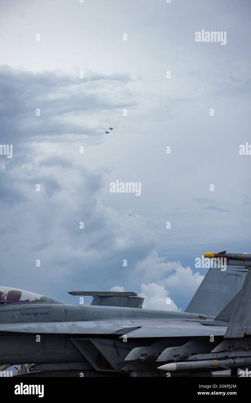 210614-N-ML137-2027 MER DE CHINE DU SUD (le 14 juin 2021) des aéronefs affectés à l’escadre aérienne Carrier (CVW) 5 survolent le seul porte-avions déployé par l’avant de la Marine américaine, l’USS Ronald Reagan (CVN 76). Ronald Reagan, le navire amiral du Carrier Strike Group 5, fournit une force prête au combat qui protège et défend les États-Unis, ainsi que les intérêts maritimes collectifs de ses alliés et partenaires dans la région Indo-Pacifique. Banque D'Images