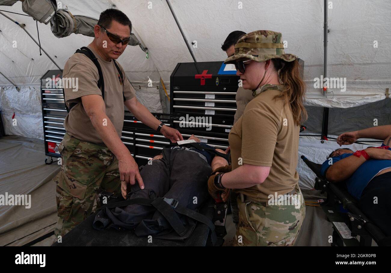 Le lieutenant colonel Cedric Wong (à gauche), 152e soutien médical du détachement 1 du groupe médical, et le capitaine Rebecca Gilbert, 152e infirmière du détachement 1 de l'équipe de transport aérien de soins intensifs (CCATT) du groupe médical, traitent un patient simulé non ambulatoire lors d'un exercice conjoint d'évaluation des risques à Kapolei, à Hawaï, le 16 juin 2021. Les aviateurs s'étaient formés avec d'autres membres de la Garde nationale dans le cadre d'un exercice conjoint de service dans un scénario de réponse aux ouragans simulé. Banque D'Images