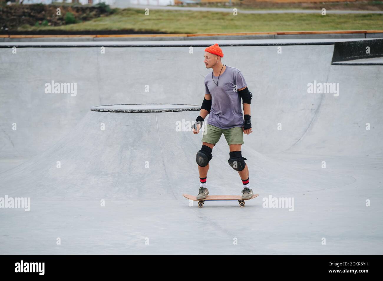 Patineuse mature dans un chapeau de montre sur un skateboard sur un sol en béton dans un parc de skate. Vue latérale, prise de vue longue. Banque D'Images