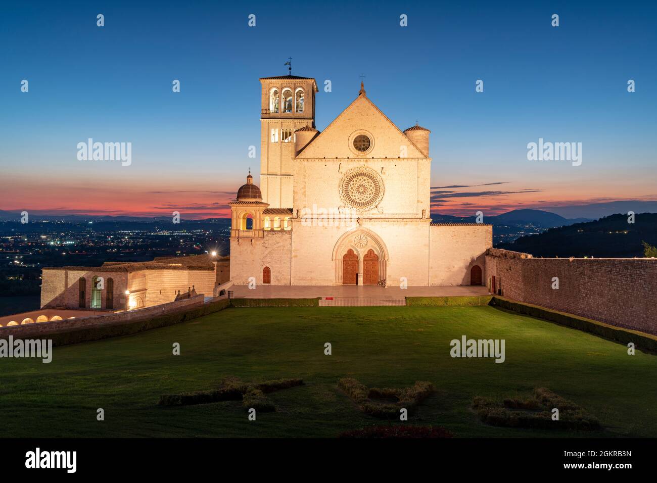 Façade de la basilique San Francesco d'Assisi, site classé au patrimoine mondial de l'UNESCO, et jardins au crépuscule, Assise, province de Pérouse, Ombrie, Italie, Europe Banque D'Images