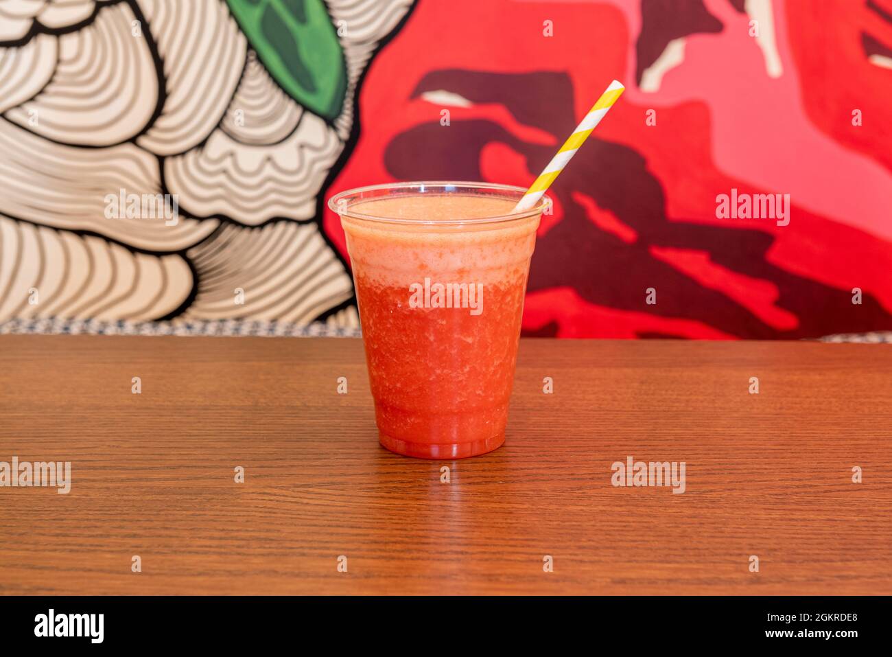 Jus de fraise dans une tasse en plastique et paille jaune Banque D'Images