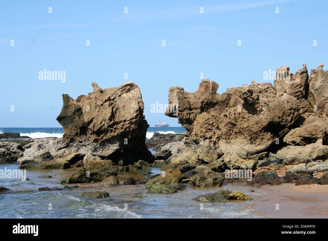 Rochers sur la plage avec un bateau au large de l'océan indien, Umdloti, Durban, Côte Nord, Afrique du Sud Banque D'Images