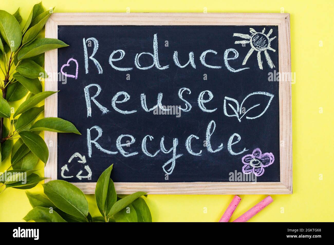 Tableau à craie affiche de recyclage Reuse sur fond jaune avec feuilles vertes et craies. Vue de dessus Banque D'Images
