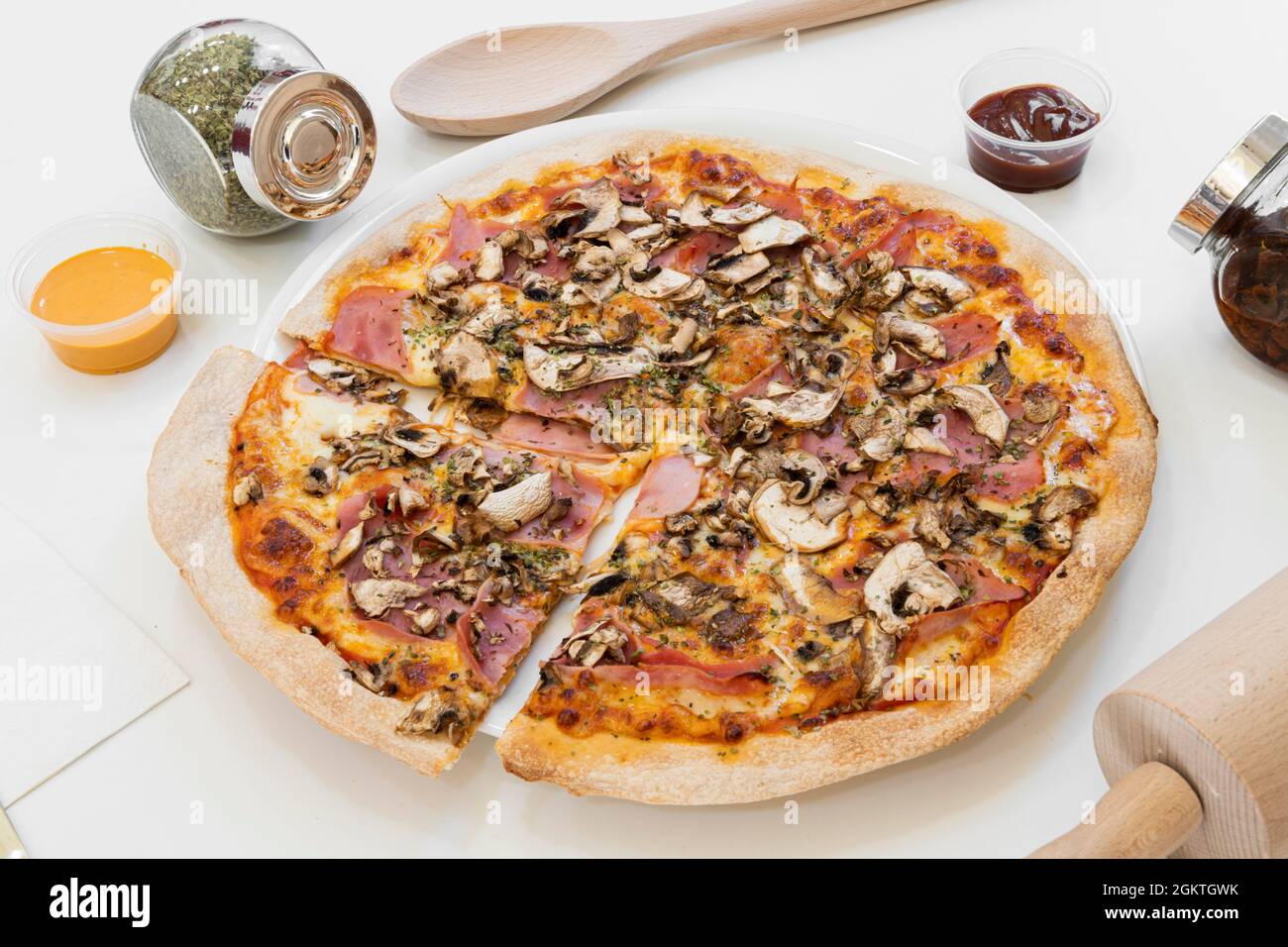 Pizza aux champignons, jambon, origan, faite avec une fine pâte sur fond blanc. Banque D'Images