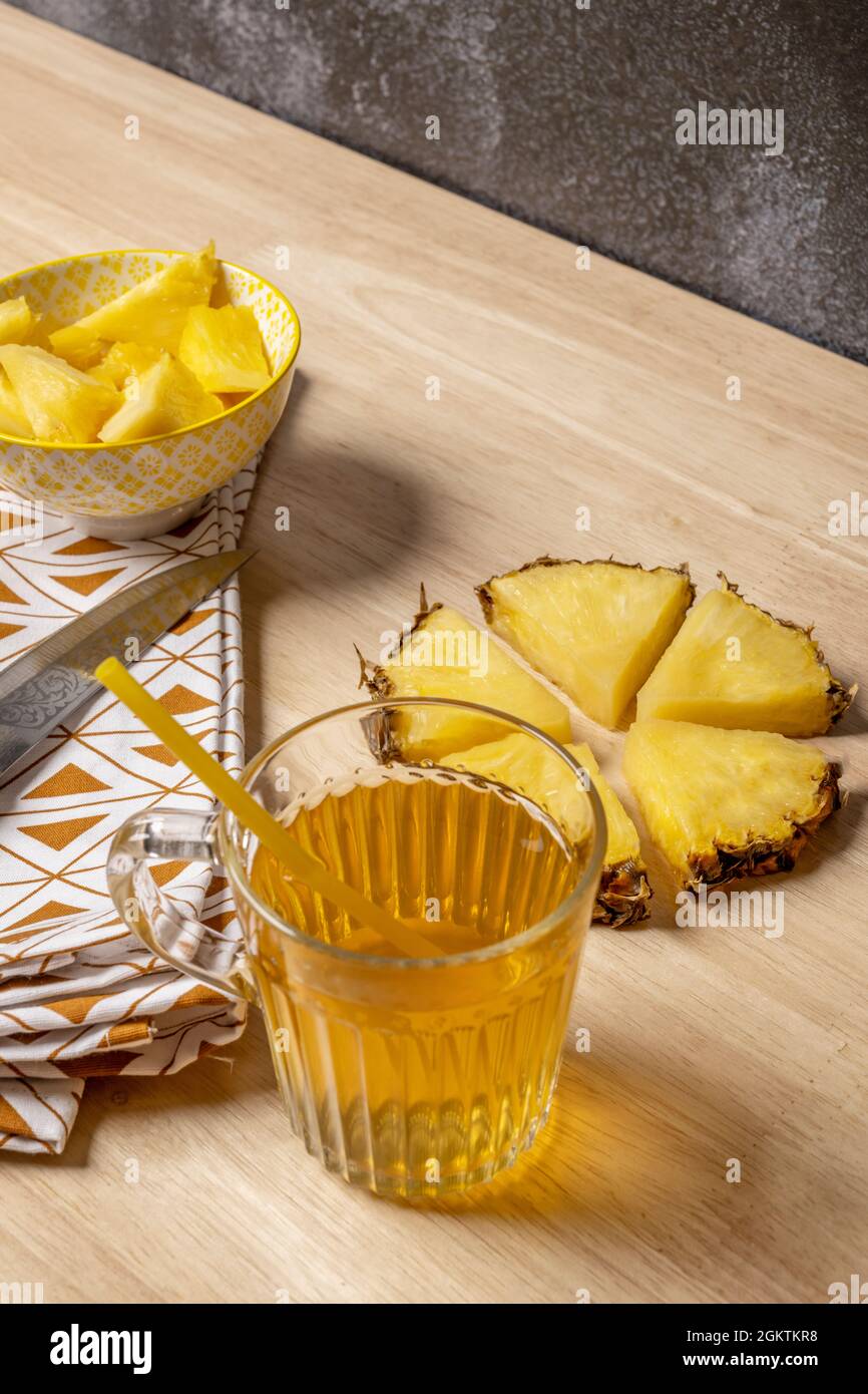 morceaux d'ananas hachés, tissu avec détails triangulaires bruns, jus d'ananas dans une tasse en verre et couteau avec motifs gravés sur la lame Banque D'Images