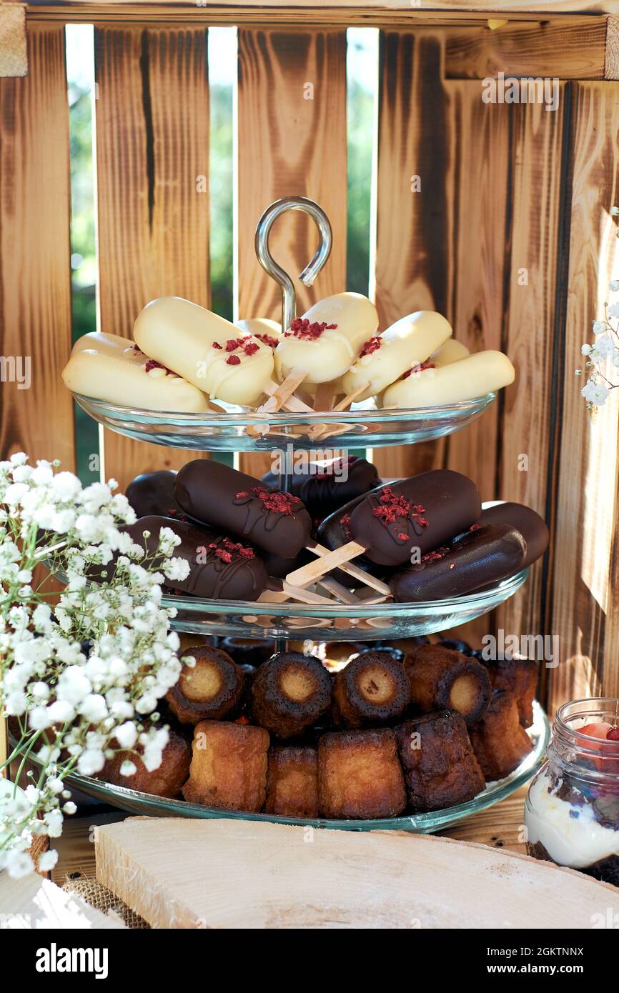 Fragment d'une table de dessert. Gâteau POPS en difficulté et chocolat noir et canules. Gypsophilia sous forme de décoration, fond en bois. Banque D'Images