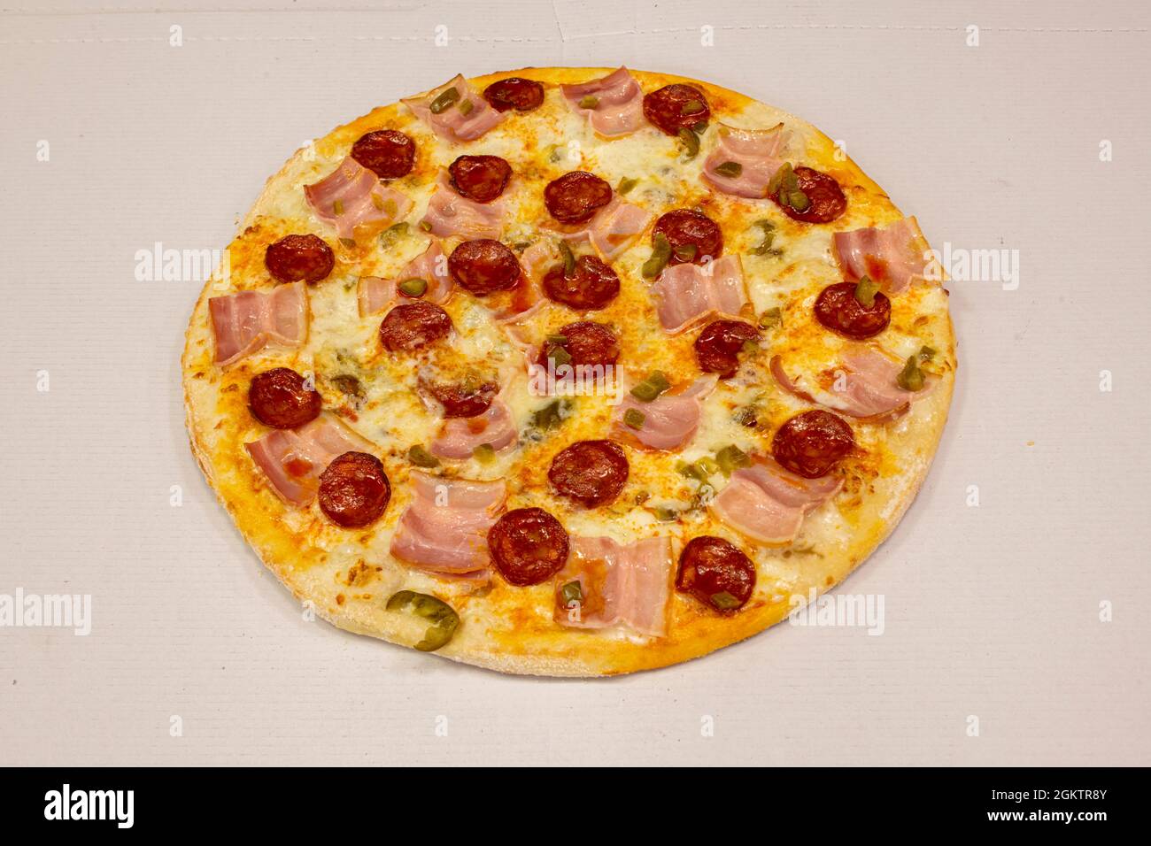 Pizza mexicaine au bacon, chorizo épicé, mozzarella et jalapenos sur carton blanc Banque D'Images