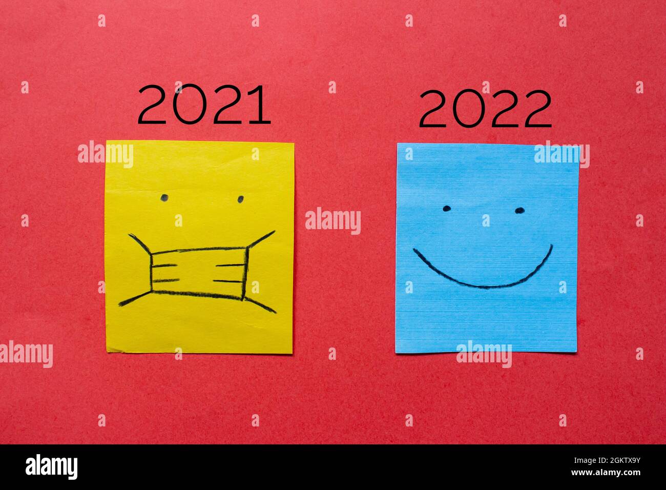 Un visage portant un masque et un visage souriant sont dessinés sur du papier. 2021 a été une année difficile à cause du coronavirus. concept nouvel espoir 2022. Banque D'Images