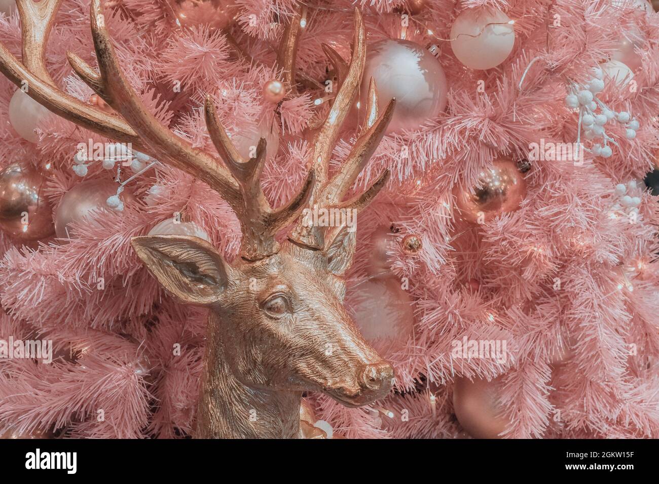 Cerf doré rose fée sur fond d'un arbre de Noël artificiel rose pâle avec diverses boules décoratives roses blanches. Banque D'Images