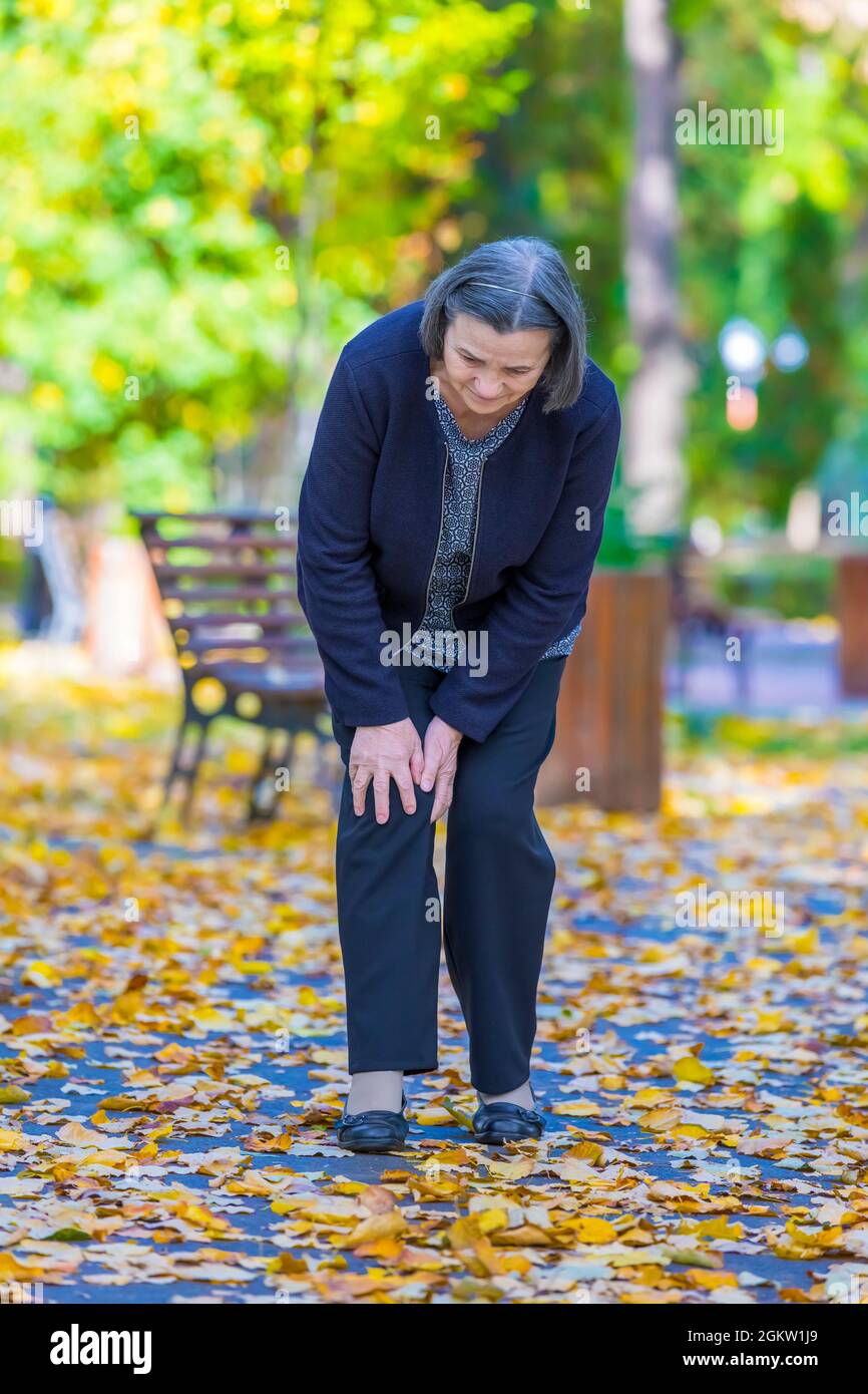 Senior woman having douleur au genou walking in park Banque D'Images