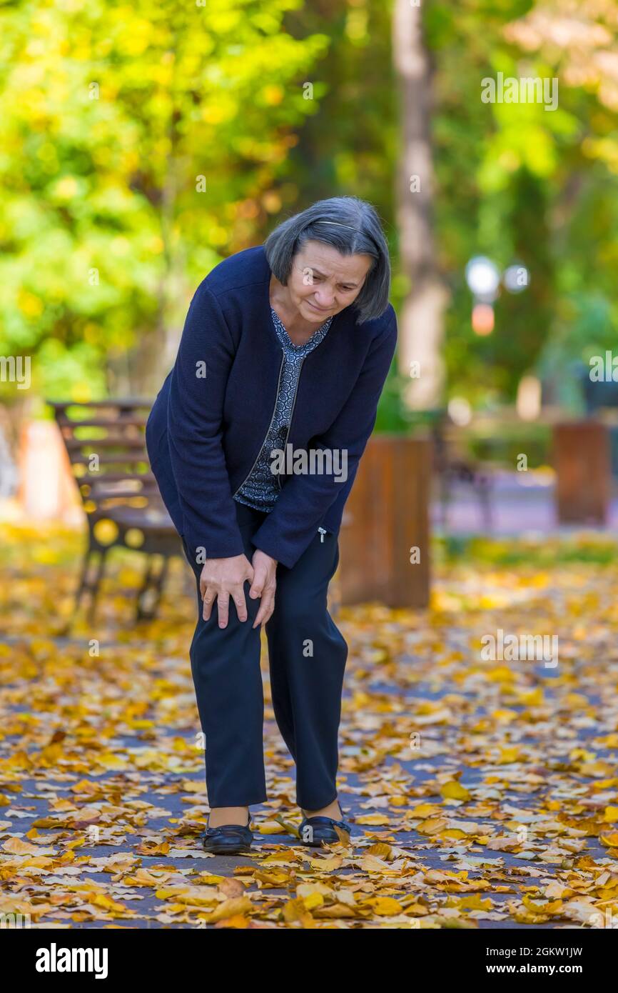 Senior woman having douleur au genou walking in park Banque D'Images