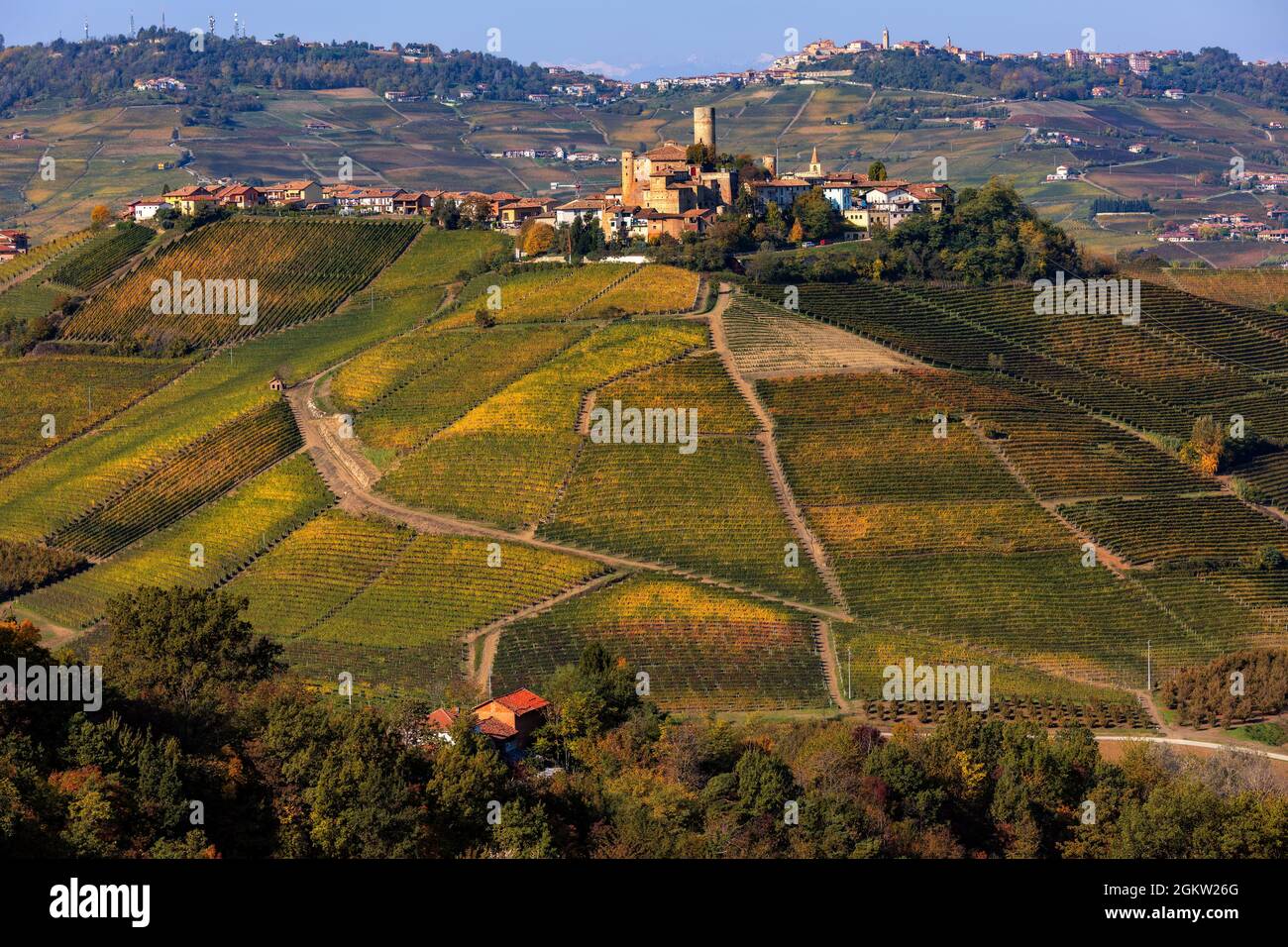Vue sur la petite ville médiévale sur la colline avec vignobles automnaux colorés dans le Piémont, dans le nord de l'Italie. Banque D'Images