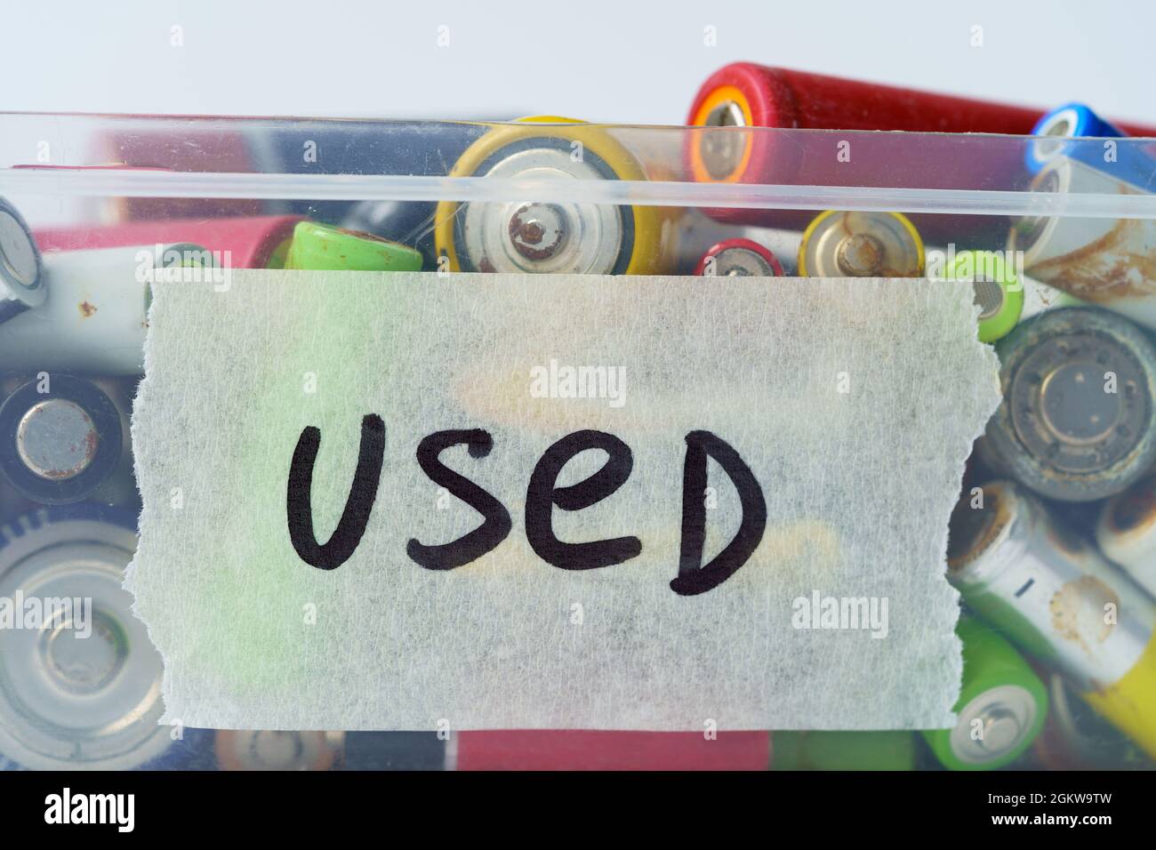 Gros plan de la batterie usagée dans un récipient en plastique sur le mur blanc. Concept de déchets dangereux électroniques. Banque D'Images