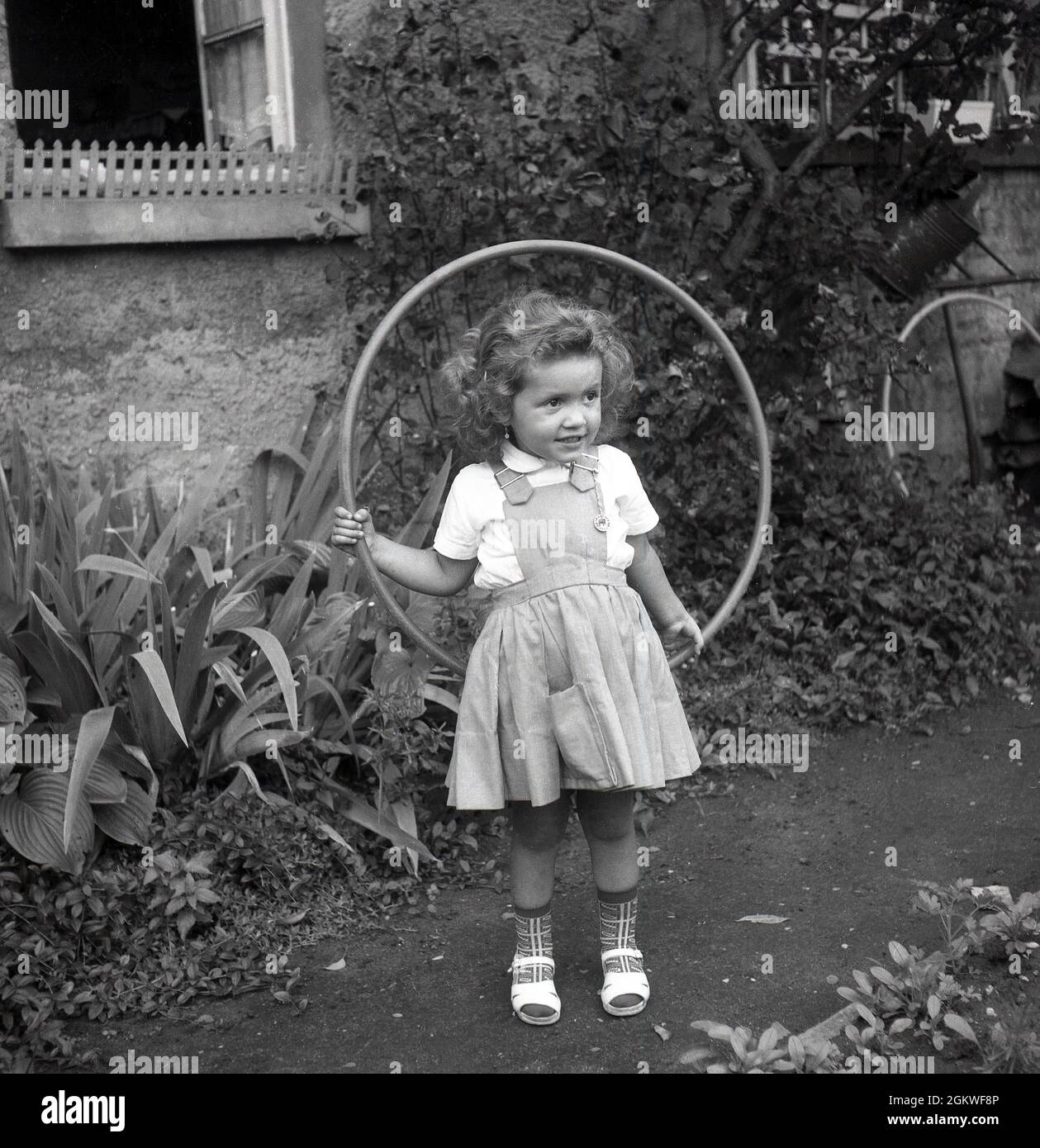 Années 1950, historique, petite fille avec un hula hoop, Allemagne.1960,  historique, à l'extérieur sur un chemin de jardin, une petite fille avec un  hula hoop, un jouet hoop, autour de sa taille,