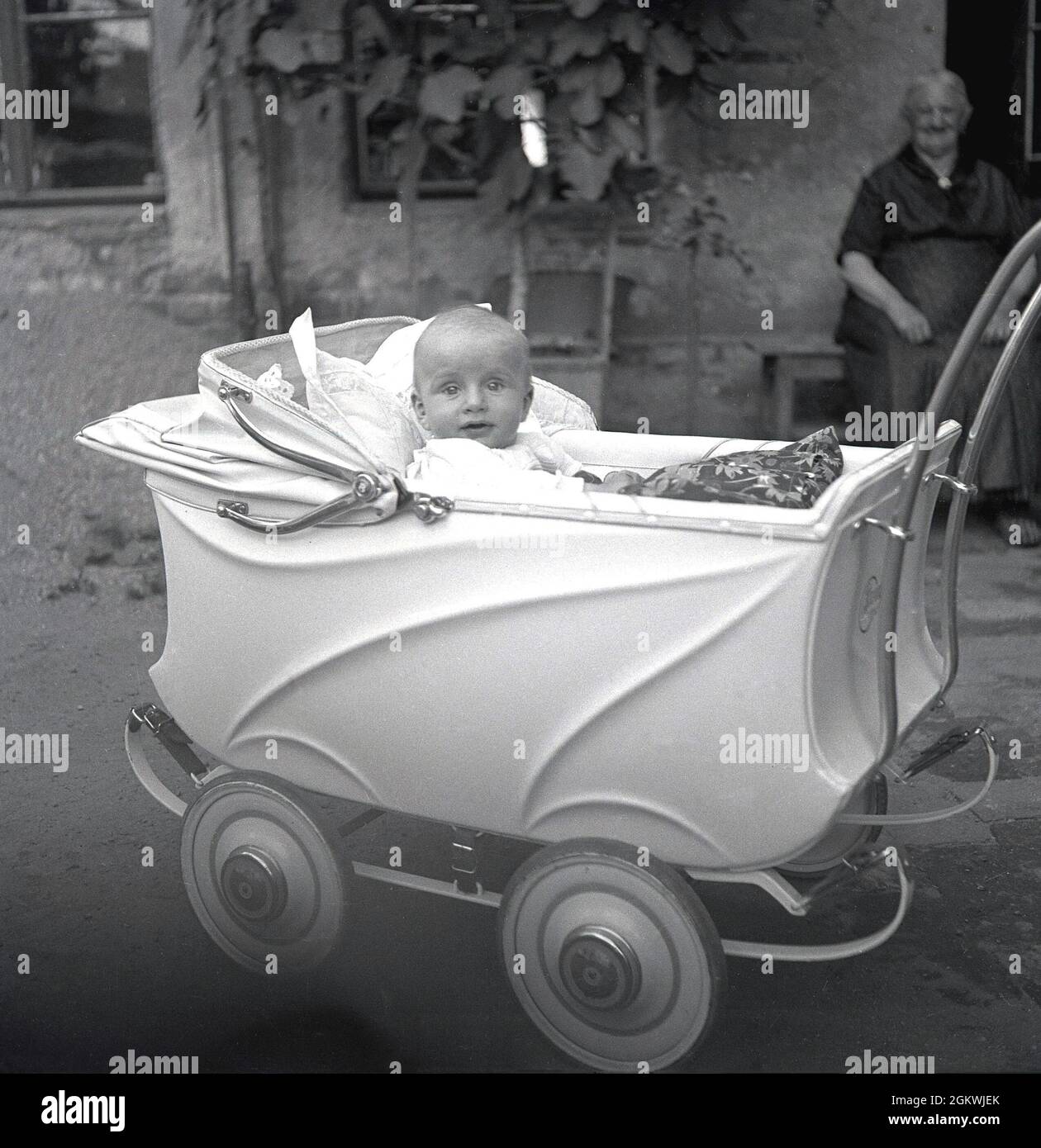Années 1950, historique, un bébé garçon assis dans un landau ou une  poussette de l'époque, à l'extérieur dans une cour, surveillé par Grandma,  Allemagne Photo Stock - Alamy