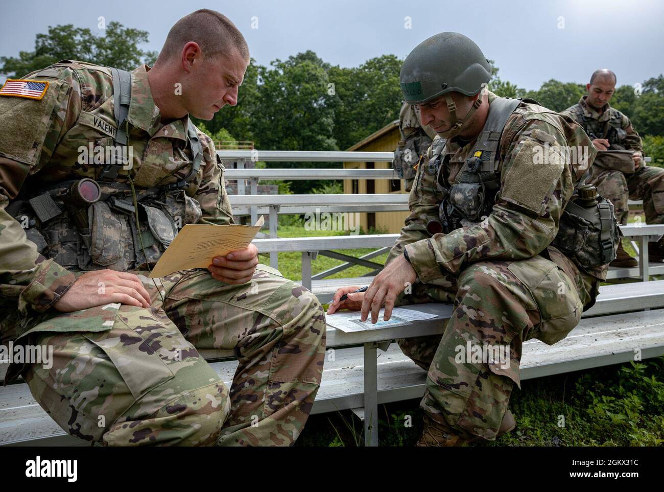 Le candidat officier Christopher Valente, à gauche, affecté à la Compagnie Bravo, 102e Régiment d'infanterie, Garde nationale de l'Armée du Connecticut, regarde une carte topographique avec le candidat de l'officier Andrew Carrillo, à droite, affecté à la Compagnie Bravo, 102e Régiment d'infanterie, Garde nationale de l'Armée du Connecticut, lors d'un événement de navigation terrestre à la réserve militaire de Stones Ranch, Niantic, Connecticut, 14 juillet 2021. Au cours de la navigation terrestre, les candidats sont chargés de trouver divers repères dispersés dans la zone d'entraînement à l'aide d'une boussole et d'une carte. Ils doivent ensuite revenir au cadre du cours Banque D'Images