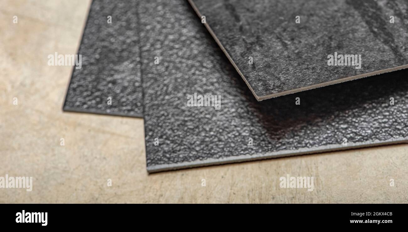 Plancher en PVC vinyle. La texture du plancher en vinyle est noire. Échantillons de revêtement en vinyle, carreaux en pvc noir sur sol en béton avant l'installation. Banque D'Images