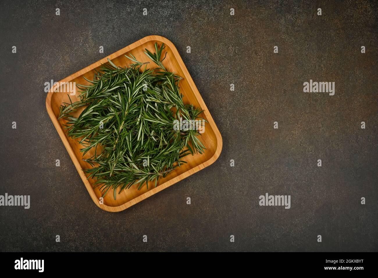 Gros plan sur les feuilles de romarin vert frais sur une assiette en bois de bambou sur la table, vue en hauteur, juste au-dessus Banque D'Images