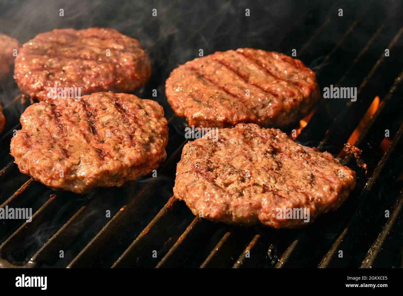 Gros plan de cuisson et de fumer du bœuf ou de la viande de porc hamburgers barbecue pour hamburgers sur barbecue feu de feu grill avec grille en fonte métallique, vue en grand angle Banque D'Images