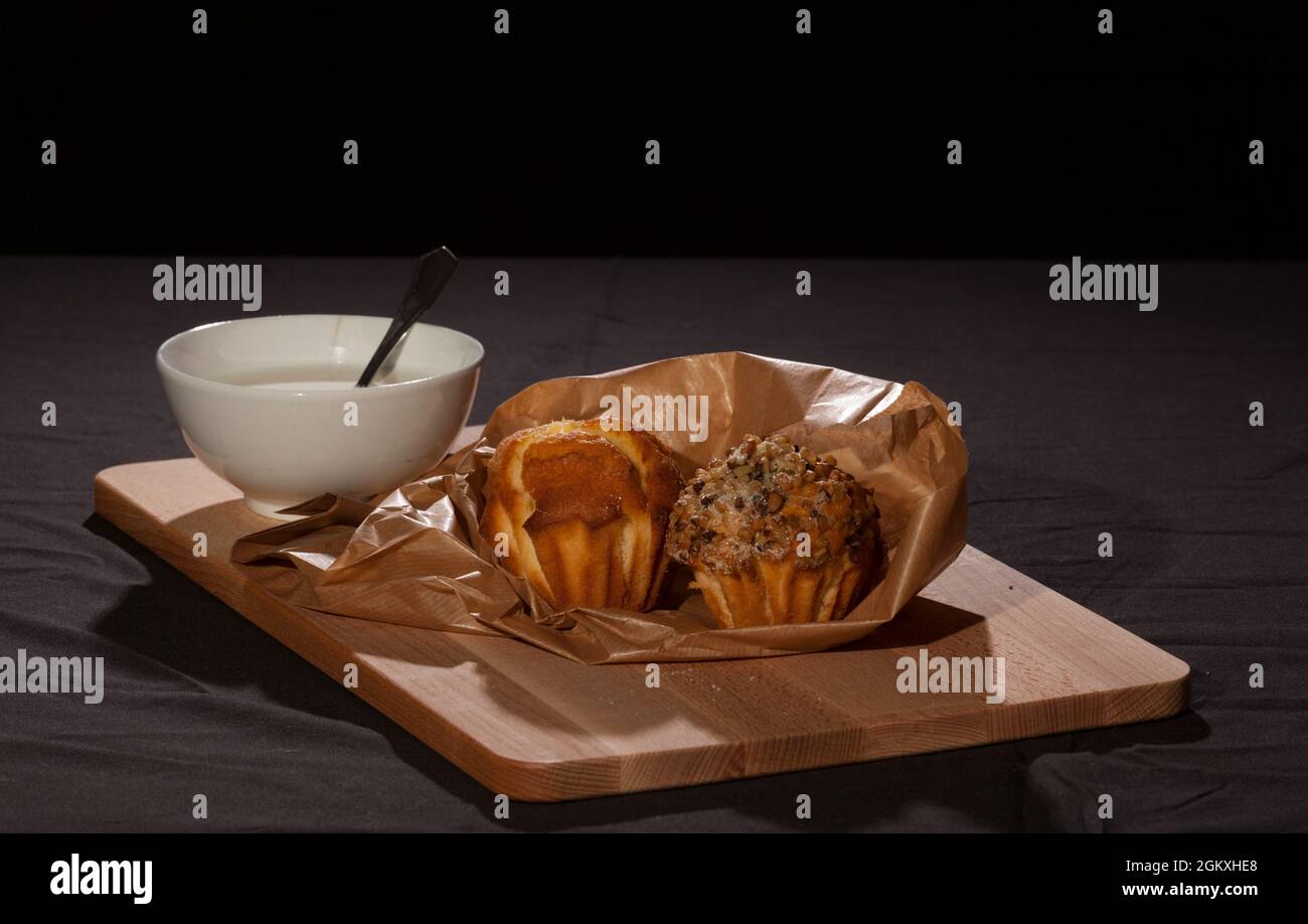 petit déjeuner, en-cas, lait avec muffins faits à la main sur plateau en bois avec fond sombre. Banque D'Images