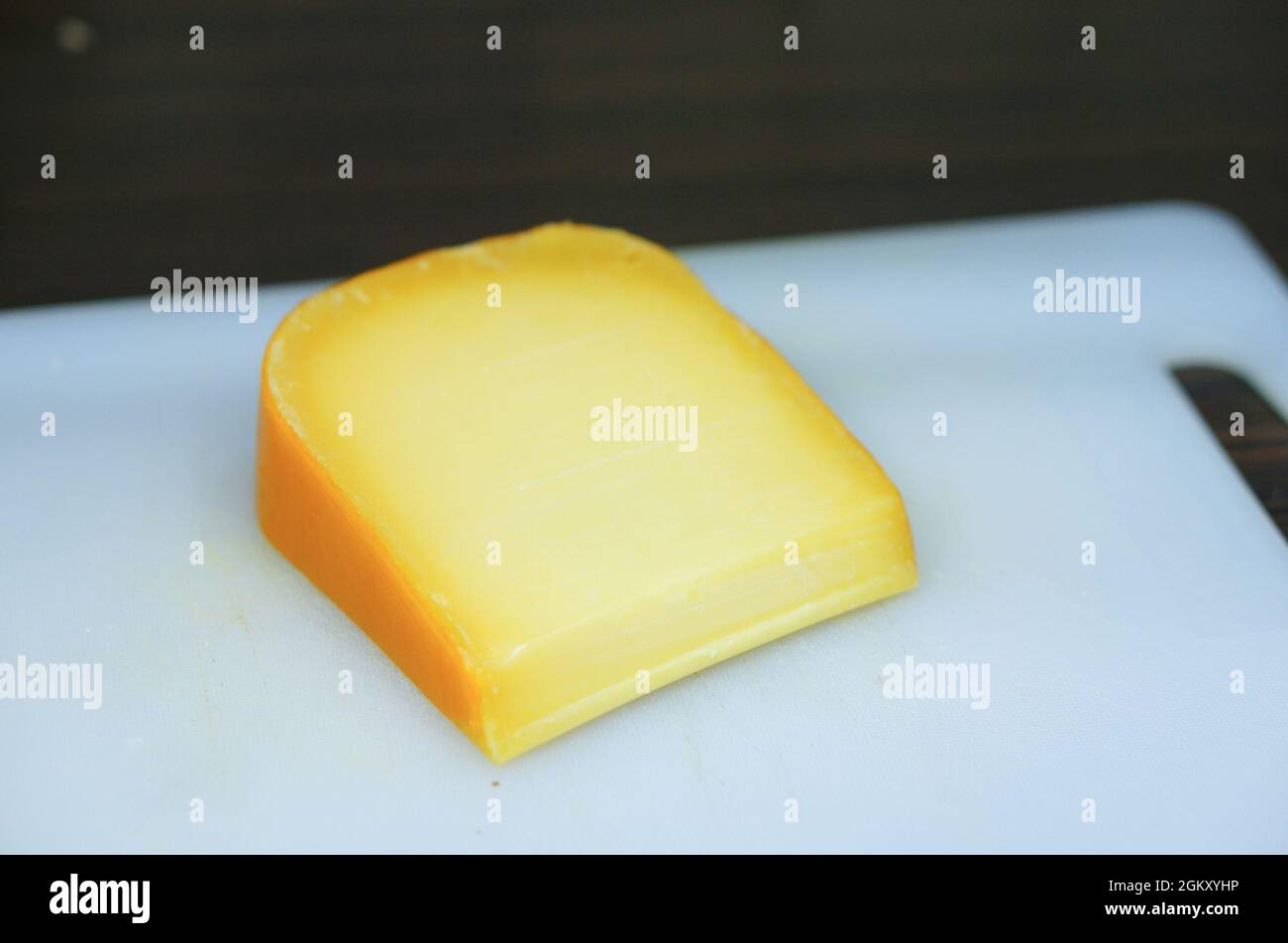 Morceau de vieux fromage Gouda sur une planche à découper bleu clair Banque D'Images