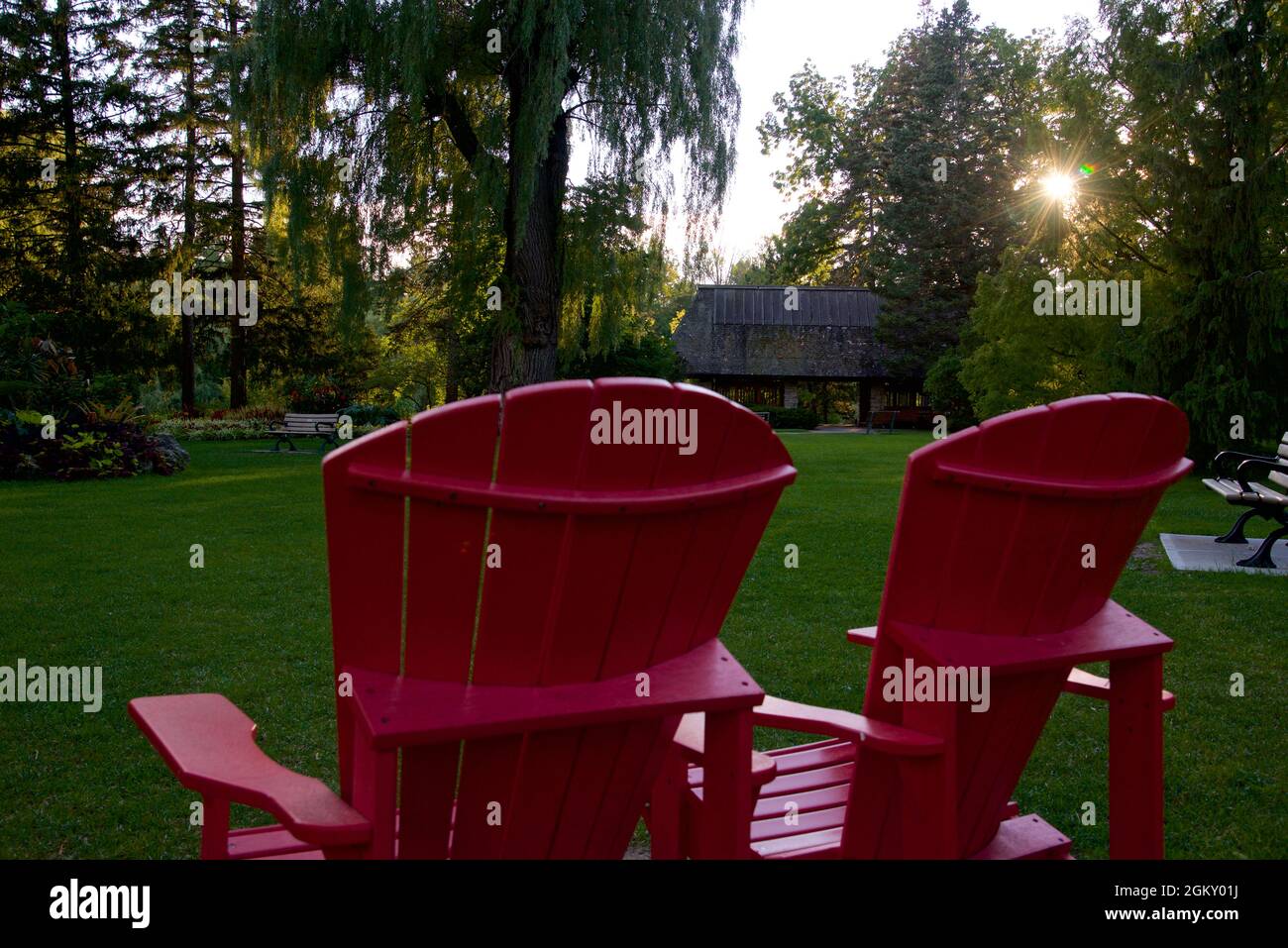 Coucher de soleil avec une lentille sur le parc public avec les chaises Adirondack. Banque D'Images