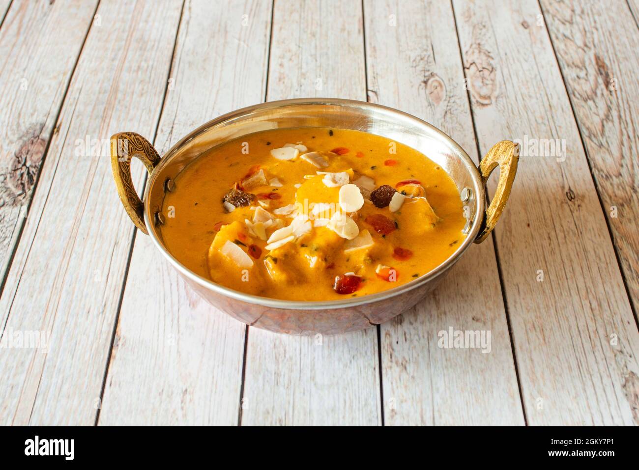 Poulet au curry de korma doux ragoût avec des tranches d'amandes et des fruits secs dans un bol en métal traditionnel Banque D'Images