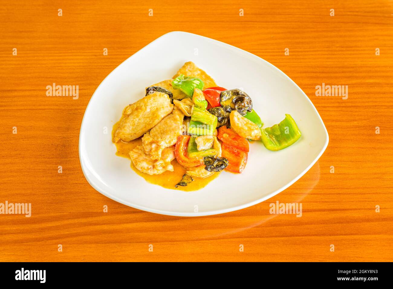 Recette de curry de poulet avec champignons et légumes chinois sautés dans le wok sur une table de couleur cerise Banque D'Images