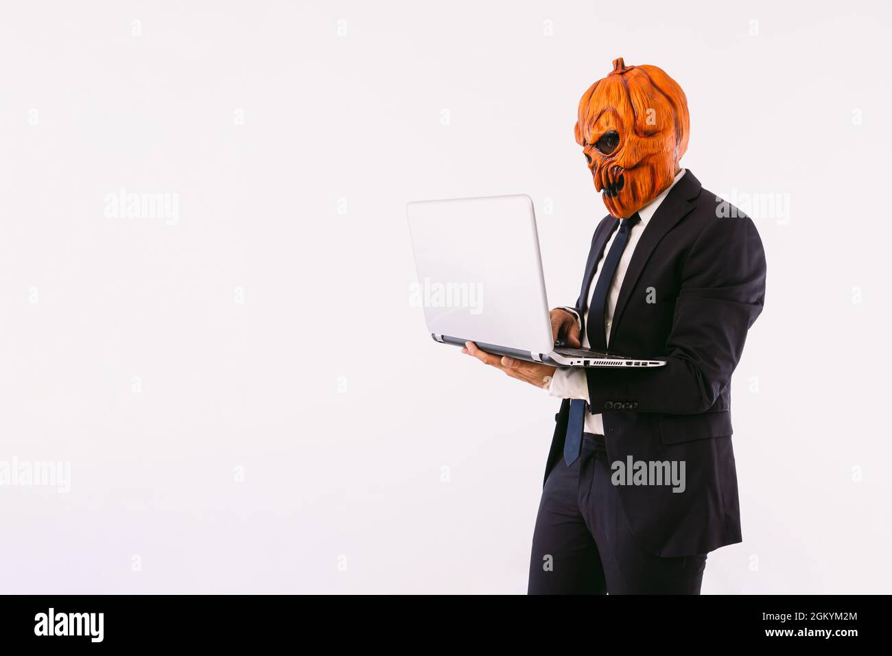 Homme portant un costume-veste, une cravate bleue et un masque de  citrouille Jack-o-lanterne, travaillant avec son ordinateur portable.  Halloween et fête du carnaval Photo Stock - Alamy