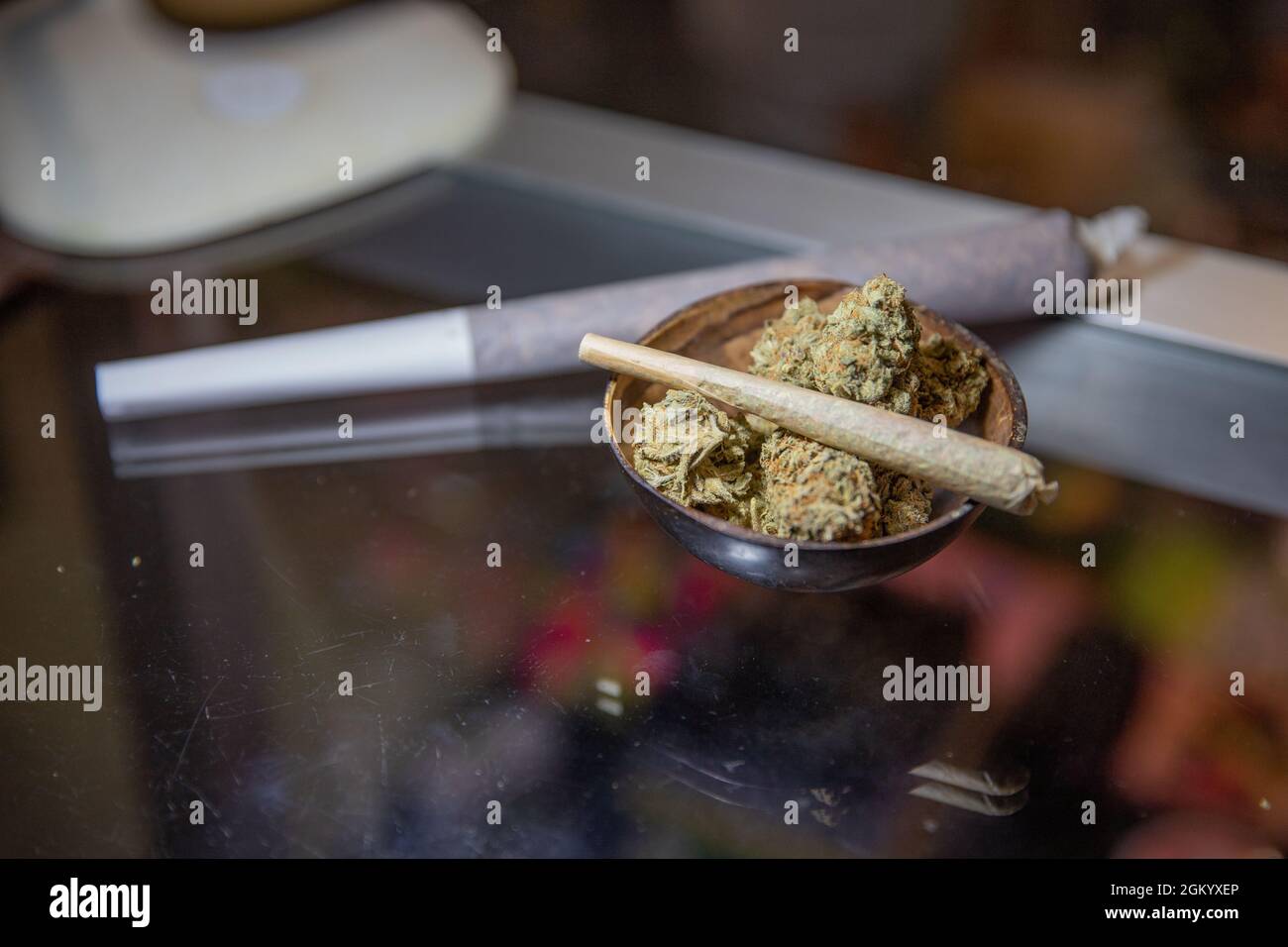 Gros plan d'un joint roulé avec de la marijuana placée sur de la marijuana brute. Banque D'Images