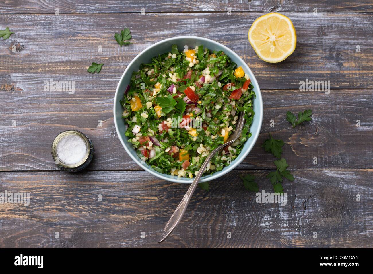 Salade orientale d'origine tabouleh avec chou kale, persil, bulgur, tomates et oignons rouges sur une table en bois, vue sur le dessus. Nourriture maison saine Banque D'Images