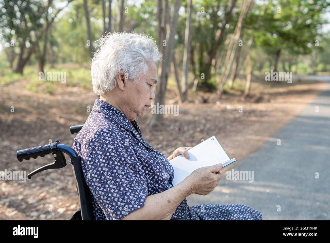 Asiatique senior ou âgée vieille femme patiente lisant un livre tout en étant assise sur le lit dans la salle d'hôpital de soins infirmiers, sain solide concept médical. Banque D'Images