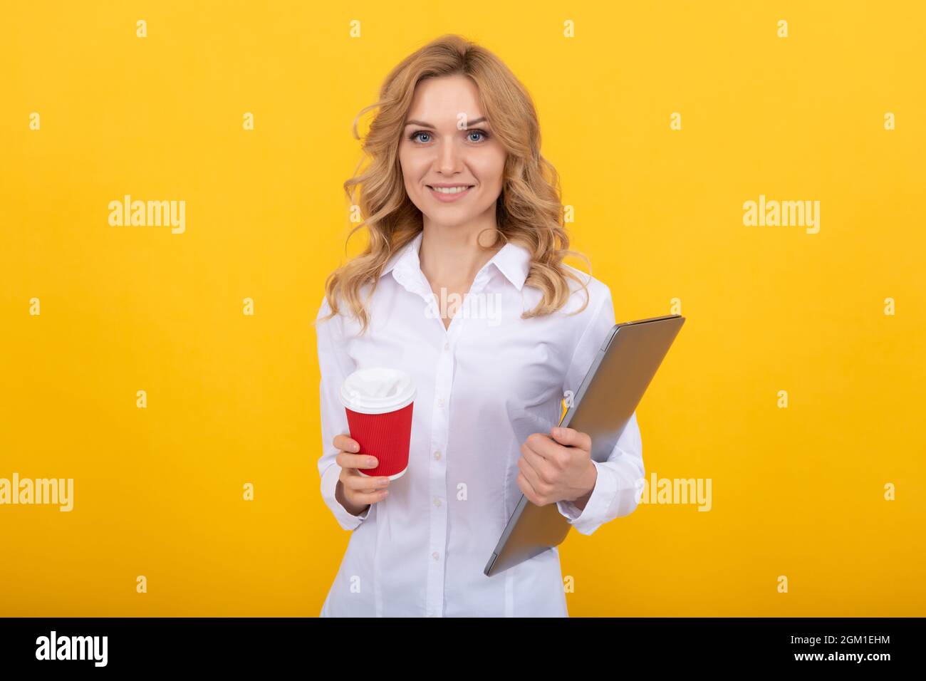 Femme heureuse enseignante avec ordinateur portable tenir une tasse de papier à emporter fond jaune, pause-café Banque D'Images